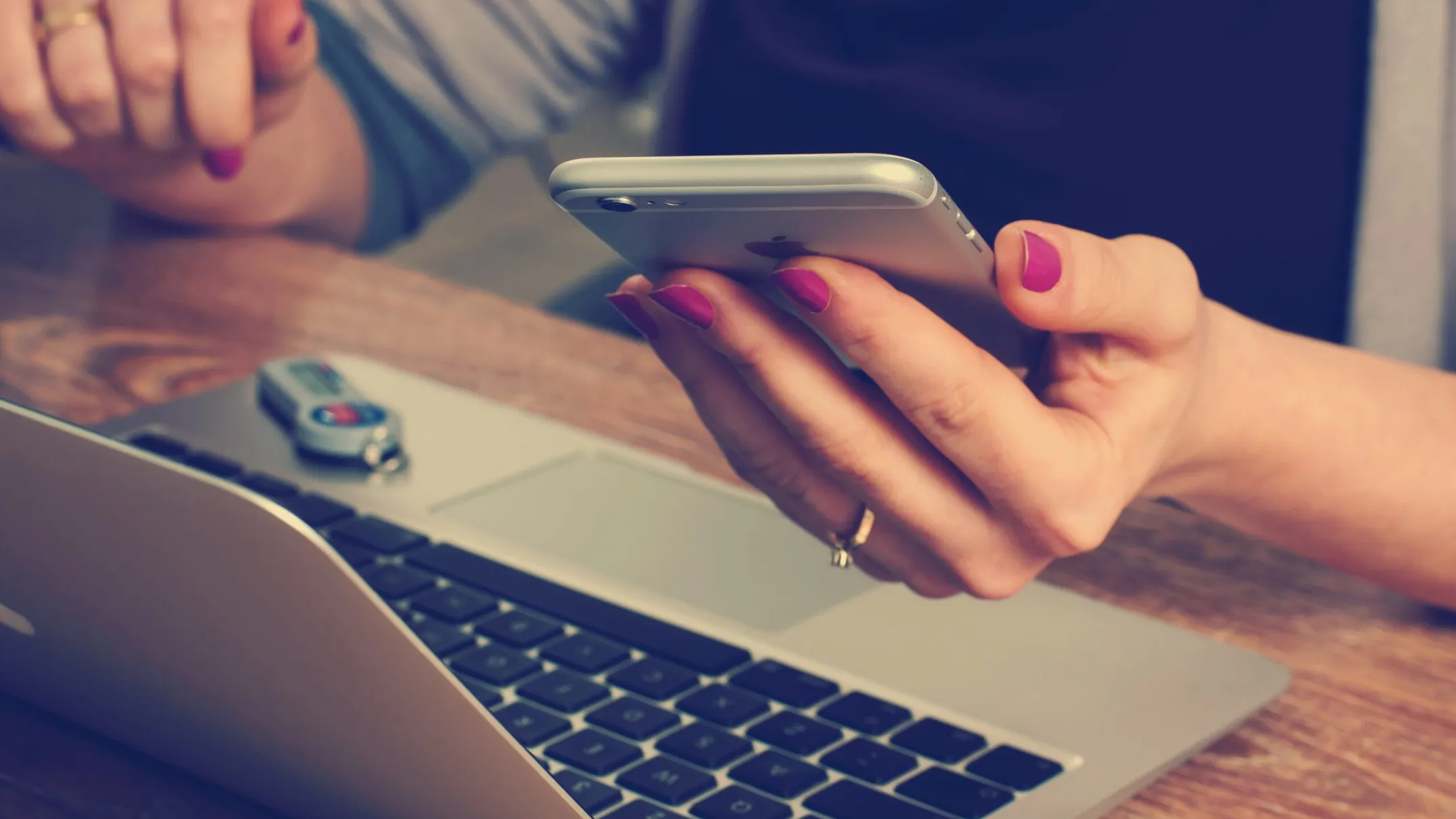 Dłonie trzymające telefon nad otwartym laptopem